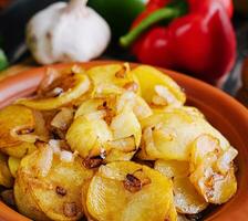 frito batatas com cebolas em de madeira bandeja foto