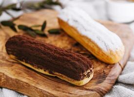 saboroso sobremesa, dois eclairs com baunilha e chocolate creme deitado foto