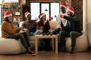 alegre animado colegas abertura espumante vinho garrafa às Natal festa dentro decorado escritório. feliz trabalhadores encontro por aí mesa com álcool e Comida dentro local de trabalho em natal véspera foto