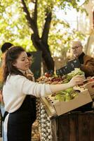 fêmea vendedor colocando preço Tag em bio agricultura produtos e trabalhando às agricultores mercado. jovem mulher pequeno o negócio proprietário vendendo fresco orgânico caseiro frutas e legumes às local ficar em pé. foto