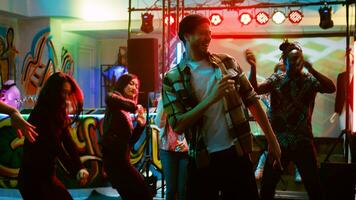 jovem adultos dançando às Boate, festa com grupo do pessoas em dança chão. diverso amigos fazendo dança movimentos em eletrônico música, tendo Diversão às discoteca. portátil tomada. foto