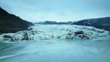 feito tiro do congeladas lago com gelo blocos, vatnajokull geleira flutuando por aí nórdico águas dentro Islândia. natural gelo panorama com icebergs e congeladas rochas, montanhas e colinas. lento movimento. foto