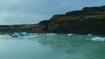 aéreo Visão do vatnajokull geleira massa dentro Islândia, espetacular gelo pedras com fendas e cavernas por aí nórdico cenário. lindo gelado blocos flutuando em islandês águas. lento movimento. foto