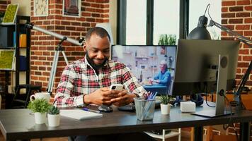 relaxado africano americano homem rolagem em dele telefone entretido de social meios de comunicação atividade. feliz alegre pessoa desfrutando ele mesmo, conversando com conectados amigos sobre a telefone dentro acolhedor à moda casa foto