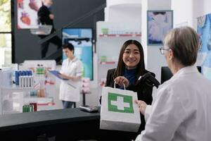 idosos farmacêutico dando medicamentos papel saco para sorridente comprador às farmacêutico balcão de pagamento. satisfeito cliente obtendo farmácia ordem a partir de farmacêutico empregado às contador escrivaninha foto