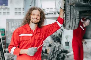 retrato feliz mecânico garagem funcionários trabalhador apreciar carro serviço. pneu substituir dentro garagem auto oficina. foto