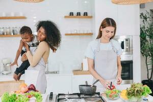 mulheres festa cozinhando refeição às amigo casa cozinha feriado com brincalhão filho criança Cuidado foto