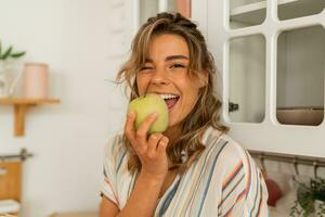 engraçado mulher comendo maçã em cozinha.dieta saudável estilo de vida conceito. foto