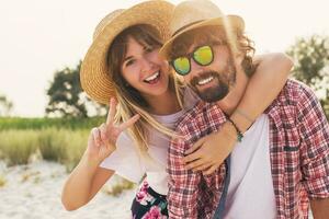 casal ou melhor amigos homem e mulher tendo Diversão em verão ensolarado de praia . vestindo Palha chapéu, oculos de sol, à moda camisas . foto