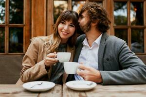 elegante casal dentro amor sentado dentro uma cafeteria, bebendo café, tendo uma conversação e desfrutando a Tempo gastar com cada outro. seletivo foco em copo. foto