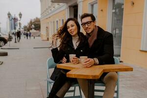 elegante casal dentro amor sentado dentro rua cafeteria e bebendo quente café enquanto viajando dentro Europa. foto