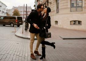 elegante casal dentro amor caminhando dentro a rua dentro Europa, tendo diversão, se beijando, abraçando. foto