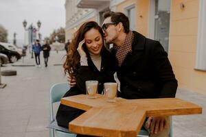 elegante casal dentro amor sentado dentro rua cafeteria e bebendo quente café enquanto viajando dentro Europa. foto