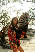 elegante mulher dentro à moda quimono com ampla ventilador e profissional faço acima posando ar livre. foto