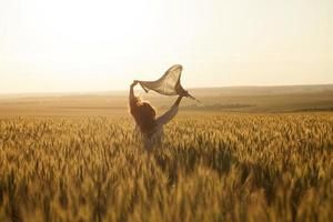 mulher com lenço na cabeça no meio de um campo de trigo maduro foto