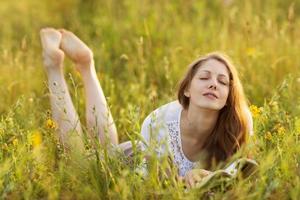 garota feliz com um livro na grama sonhando foto
