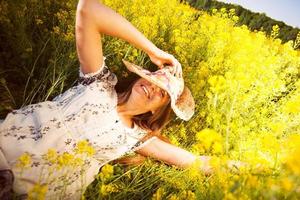 mulher feliz deitada entre flores silvestres amarelas foto