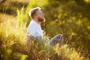 homem feliz sentado na grama e sonhando foto