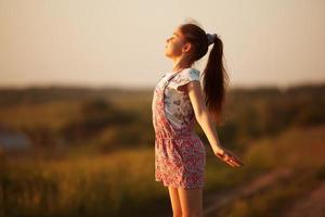 menina feliz de frente para o sol foto