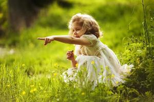 menina com uma flor indica algum lugar com a mão foto