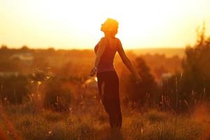 mulher feliz em um campo ao pôr do sol foto