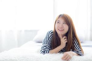jovem mulher asiática mentindo e sorria enquanto acorda. foto