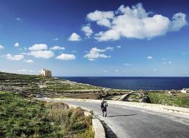 pastor na estrada perto do forte e vista da costa mediterrânea da ilha de gozo em malta foto