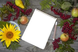 bloco de notas com uma folha de papel em branco. Rowan em um fundo de madeira foto