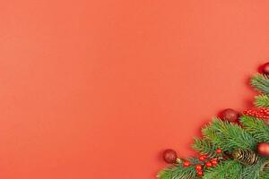 Natal festivo plano deitar composição com vermelho bolas decoração, bagas e abeto árvore galhos em vermelho fundo. topo visualizar. cópia de espaço. foto