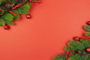 Natal festivo plano deitar composição com vermelho bolas decoração, bagas e abeto árvore galhos em vermelho fundo. topo visualizar. cópia de espaço. foto