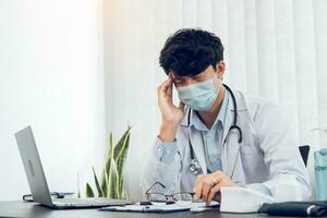 médico jovem asiático sendo exausto e esgotado na sala do escritório. foto