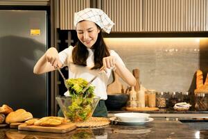 dona de casa asiática preparando legumes frescos para fazer salada no balcão da cozinha em casa. foto