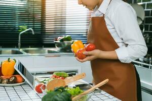 a dona de casa está cozinhando olhando a receita no tablet. foto