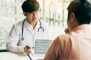 médico asiático falando com o paciente na clínica enquanto usa o tablet explicando a condição do paciente e o resultado do tratamento. foto