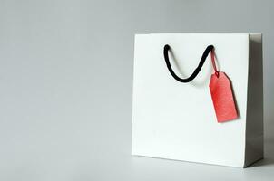 branco compras papel saco com vermelho em branco preço tag em branco fundo para Preto Sexta-feira compras venda conceito. foto