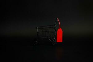 Preto compras carrinho com vermelho em branco preço tag em Preto fundo para Preto Sexta-feira compras venda conceito. foto