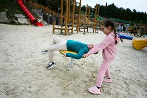 pequeno menina e dela irmão tendo Diversão em a Parque infantil dentro a parque. foto