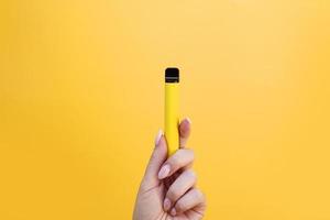 cigarro eletrônico descartável amarelo em mão feminina foto