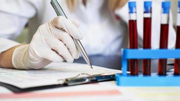 mulher trabalhando com amostras de sangue em laboratório, closeup foto