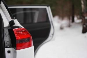 carro branco com farol vermelho e porta aberta - floresta de inverno foto