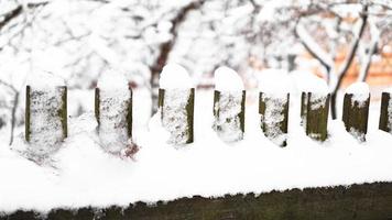 portão de cerca de madeira coberto de neve branca em forte nevasca foto