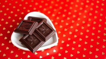 chocolate em um prato em forma de coração sobre fundo vermelho foto