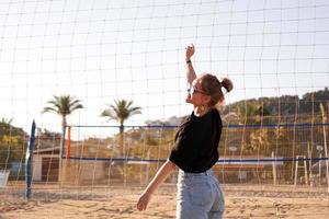 retrato de uma mulher atraente perto da rede de vôlei na praia foto