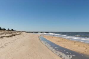 Eu Amado a Veja do isto de praia Como a ondas maltratado a costa. a cristas do a ondas faço isto Veja duro. a lindo azul céu com não nuvens dentro local faço isto Veja gostar uma lindo verão dia. foto