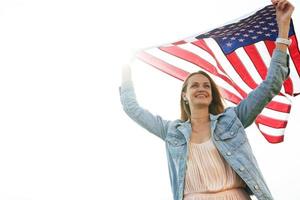 uma garota com um vestido coral e uma jaqueta jeans segura a bandeira dos EUA