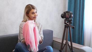 mulher blogueira grava vídeo. ela mostra peruca rosa foto