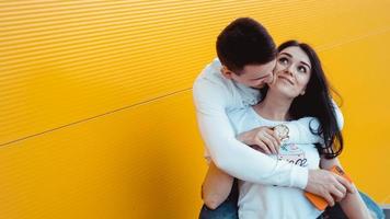 jovem casal adorável posando juntos e se abraçando sobre um fundo amarelo foto