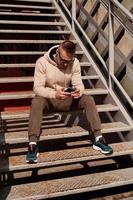 um jovem se senta na escadaria da cidade. estilo urbano foto