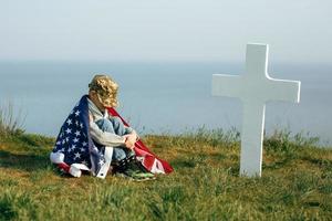 um jovem com um boné militar, coberto pela bandeira dos EUA foto