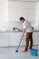 homem limpando a casa com esfregão foto